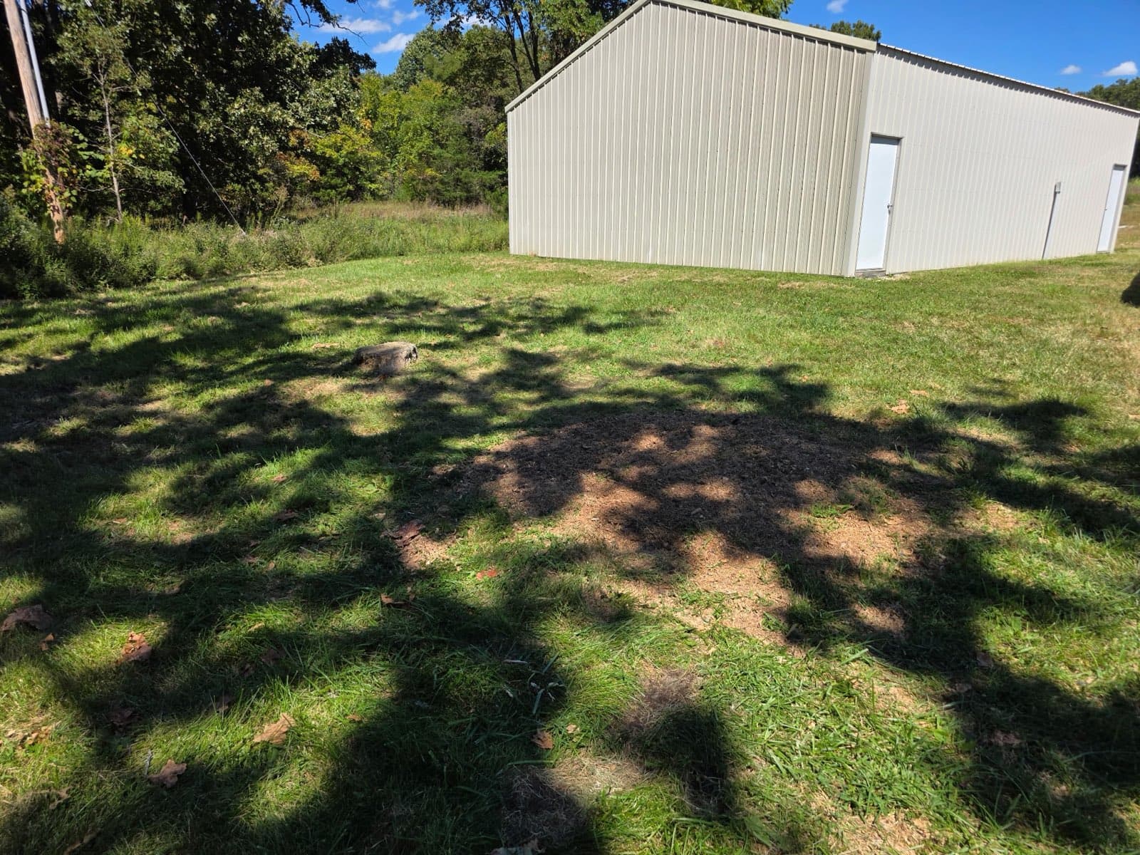 Lawn outside the metal shop building with the oak stump gone and the ground smoothed